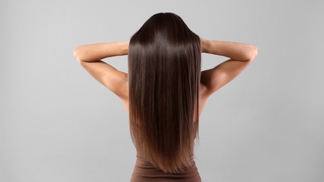 Uma mulher de pele clara exibe seu cabelo longo, ou cabelão, cortado em formato de U